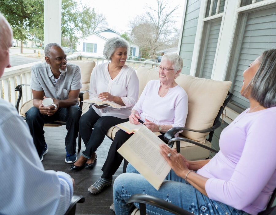 A group of diverse retired senior adults enjoy participating in a book club in an active retirement community. They are sharing their opinions of the book.